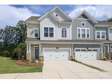 View of a charming townhome with a manicured lawn, two-car garage, and neutral color scheme at 8221 Houser St, Cornelius, NC 28031