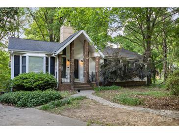Charming home featuring a brick chimney and inviting front entrance enveloped by lush greenery at 1407 Jodhpur Ct, Charlotte, NC 28212