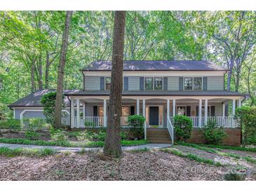Charming two-story home with a welcoming front porch, surrounded by lush landscaping and mature trees at 2310 Vestry Pl, Charlotte, NC 28270