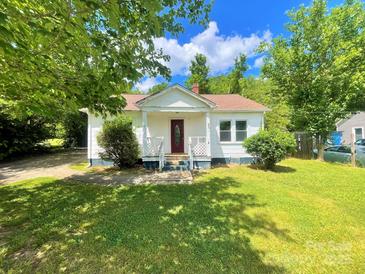 Charming single-story home with a red front door, lush green lawn, and mature trees providing shade at 736 7Th Sw Ave, Hickory, NC 28602