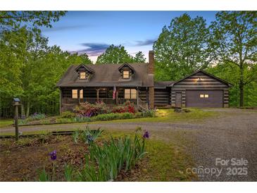 Charming log cabin home with a well-manicured lawn and beautiful flower beds, offering a serene setting at 140 Hearthstone Dr, Statesville, NC 28677