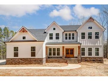 Charming two-story home with stone accents, a covered porch, and a well-manicured lawn at 206 Streamwood Rd # 32, Troutman, NC 28166