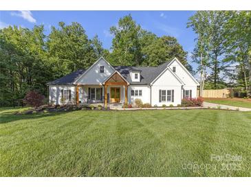 Beautiful white farmhouse with a manicured lawn and inviting front porch at 518 Maynard Farm Ln, Stanley, NC 28164
