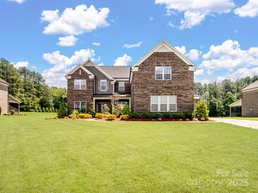 Beautiful two-story brick home featuring a large front yard and well-maintained landscaping at 709 Cavesson Way, Monroe, NC 28110