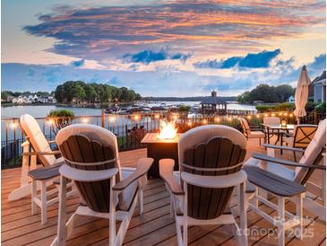 Outdoor lake view deck featuring Adirondack chairs and a cozy fire pit, perfect for enjoying serene waterfront evenings at 7220 Swansea Ln, Cornelius, NC 28031