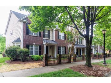 Row of brick townhomes featuring black shutters and wrought iron fence along a tree lined sidewalk at 9532 Cadman Ct, Cornelius, NC 28031