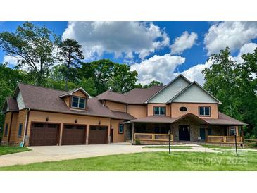 Stunning two-story home featuring a three-car garage, inviting front porch, and lush green lawn at 1140 Fern Hill Rd, Mooresville, NC 28117