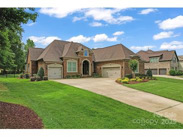 Beautiful brick home featuring a three-car garage, manicured lawn and lush landscaping at 1400 Delaney Dr, Matthews, NC 28104