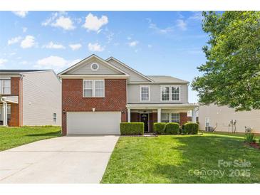 Charming two-story home with a brick facade, manicured lawn, and attached two-car garage at 312 Farm Springs Dr, Mount Holly, NC 28120