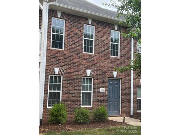 A brick two-story home featuring white-trimmed windows and a gray front door, complemented by lush green bushes at 135 Locomotive Ln # 106, Mooresville, NC 28115