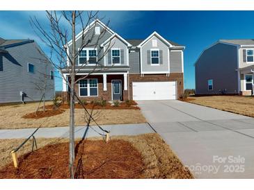 Charming two-story home with gray siding, brick accents, and a two-car garage under a bright blue sky at 1817 Augustine St, Monroe, NC 28112