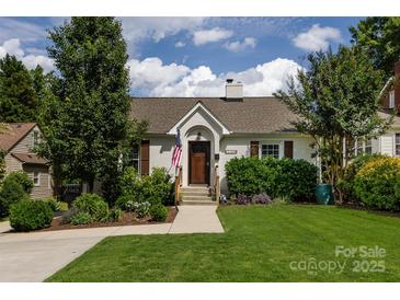 Charming one-story home with an American flag, lush landscaping, a stone chimney, and a well-manicured lawn at 2124 Chatham Ave, Charlotte, NC 28205