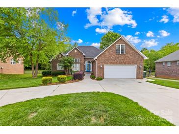 Charming brick home featuring an attached two-car garage, blue front door, and manicured landscaping at 229 River Birch Cir, Mooresville, NC 28115