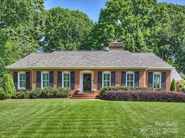 Charming brick home featuring manicured lawn, mature trees, and neatly trimmed shrubs at 3620 Champaign St, Charlotte, NC 28210