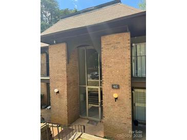 Brick building featuring an arched entry, glass doors, and stairway entrance in daylight at 415 Orchard Trace Ln # 8, Charlotte, NC 28213