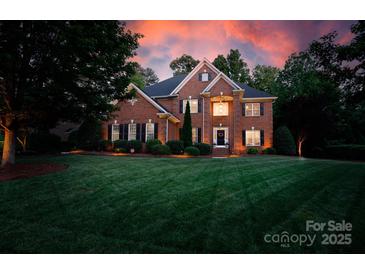 A brick two-story home features a lush green lawn, mature trees, and traditional architectural details at 905 Patricians Ln, Monroe, NC 28110