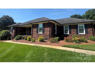 Charming brick ranch-style home with a well-manicured lawn and mature landscaping at 6339 River Front Dr, Harrisburg, NC 28075