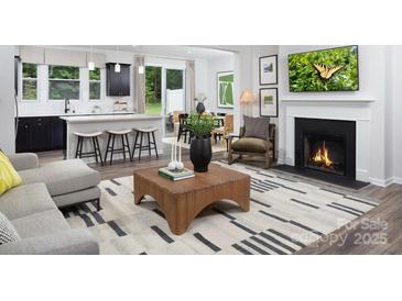 Open-concept living room with modern furnishings, a fireplace, and a spacious kitchen island at 12305 Gambrell Dr, Charlotte, NC 28278