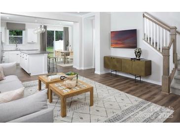 Inviting living room with hardwood floors, patterned rug, and modern decor; open to kitchen and dining area at 12309 Gambrell Dr, Charlotte, NC 28278