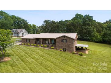 Beautiful brick home with a metal roof, covered carport, and a well-manicured lawn at 1512 Mount Ulla Hwy, Mooresville, NC 28115