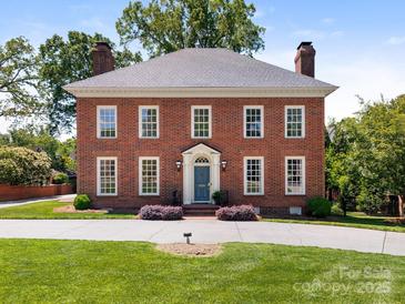 Beautiful brick two-story home featuring mature landscaping, a gray roof, and a blue front door at 208 Huntley Pl, Charlotte, NC 28207