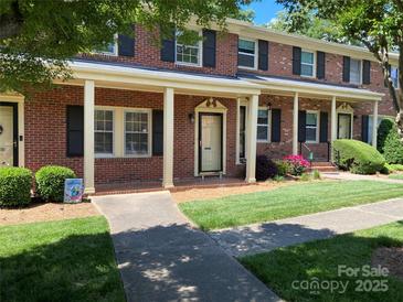 Charming brick townhouse featuring a covered front porch, black shutters, and manicured lawn at 623 S New Hope Rd # 9, Gastonia, NC 28054