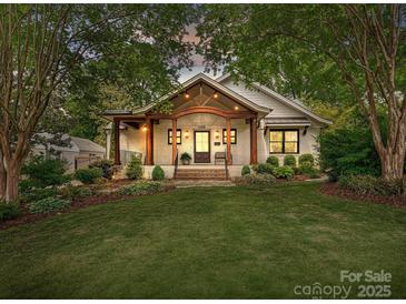 Charming white brick home featuring a covered porch with stylish wood beams and lush landscaping at 1139 Yale Pl, Charlotte, NC 28209