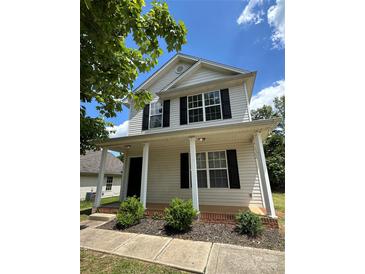 Two-story home with vinyl siding, black shutters, a front porch, and manicured landscaping at 1300 Braveheart Ln, Charlotte, NC 28216