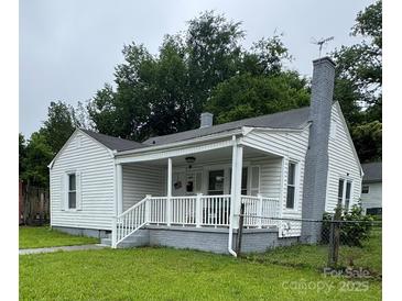Charming home featuring a covered front porch, white siding, and a painted brick chimney at 247 E Cabarrus Ave, Concord, NC 28025