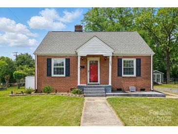 A brick house featuring black window shutters, a red front door, and a well-manicured lawn at 604 Meadowbrook Rd, Kings Mountain, NC 28086