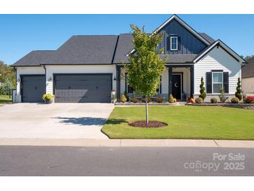 Charming two-story home with a three-car garage, beautiful landscaping, and inviting front porch at 7112 Irongate Dr, Indian Land, SC 29707