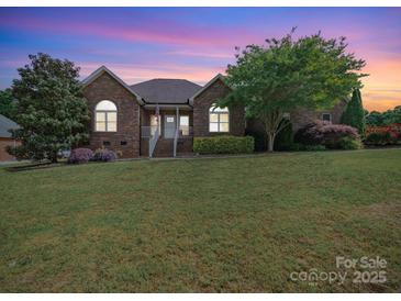 Charming brick home with manicured lawn and mature trees set against a vibrant twilight sky at 1021 Mallard Landing Dr, Monroe, NC 28110
