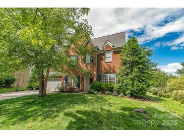 Charming two-story brick home with manicured lawn, mature trees, and a two-car garage at 10418 Goosefoot Nw Ct, Concord, NC 28027