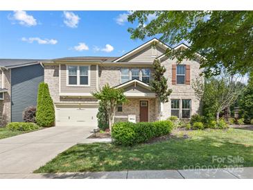 Charming two-story brick home with a well-manicured lawn, landscaping, and an attached two-car garage at 300 Hidden Cove Ln, Matthews, NC 28104