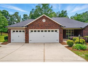Well-maintained brick home featuring a spacious driveway leading to a three-car garage with white doors at 4860 Sherborne Dr, Harrisburg, NC 28075