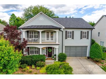 Charming two-story home with a covered porch, balcony, manicured landscaping, and an attached two-car garage at 1020 Forbishire Dr, Matthews, NC 28104
