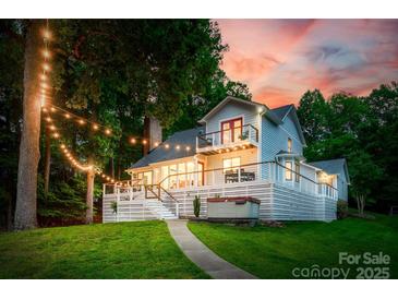 Lake house featuring a spacious deck, hot tub, balcony, and string lights creating a cozy outdoor ambiance at sunset at 18028 Broken Woods Rd, Charlotte, NC 28278