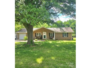 Charming brick home with a well-manicured lawn, mature shade tree, and inviting front porch with benches at 6573 Weldon Nw Cir # 22, Concord, NC 28027
