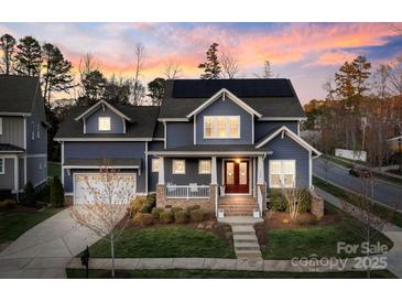 Charming two-story home featuring a welcoming front porch, solar panels, and well-maintained landscaping at 1502 Matthew Mcclure Cir, Davidson, NC 28036