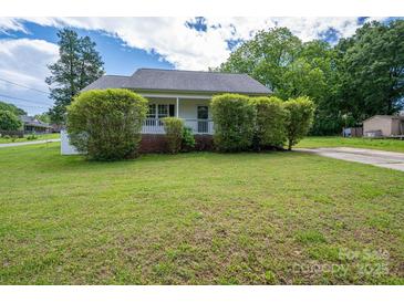 Charming home featuring a covered front porch and a well-maintained lawn and mature landscaping at 210 Park St, Bessemer City, NC 28016