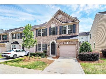 Charming brick townhome featuring a one-car garage and lush landscaping at 3251 Park South Station Blvd, Charlotte, NC 28210