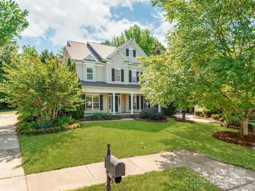 Inviting two-story home with a lush green lawn, mature trees, and a charming front porch at 533 Montgrove Nw Pl, Concord, NC 28027