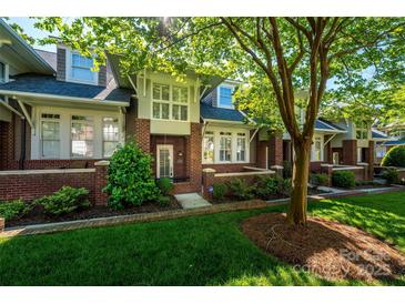 Charming brick townhome featuring lush landscaping, a covered front porch, and a well-manicured lawn at 6312 Mission Pl, Charlotte, NC 28210