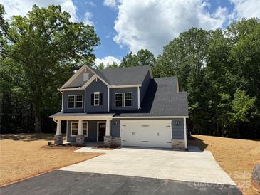 Two-story home with a two car garage, welcoming front porch, and classic dark gray siding at 910 Westminster Dr, Statesville, NC 28677