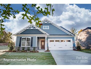 Charming single-Gathering home with blue siding, stone accents, a two-car garage, and manicured lawn at 106 S Inneswood Ln # 31, Mooresville, NC 28115