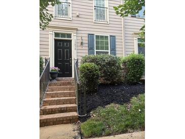 Charming two-story townhome featuring a black front door, brick stairs, and manicured landscaping at 13838 Winmau Ln, Huntersville, NC 28078