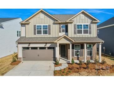 Charming two-story home featuring a brick and siding exterior, attached garage, and well-maintained landscaping at 15004 Meadows Hunt Ln # 155, Huntersville, NC 28078