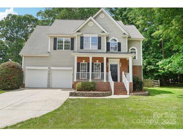 Charming two-story home features a well-manicured lawn, two-car garage, and inviting front porch at 15108 Castlebridge Ln, Matthews, NC 28104