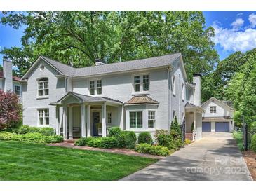 Charming white brick home with lush landscaping and a welcoming front porch with swing at 2627 Hampton Ave, Charlotte, NC 28207