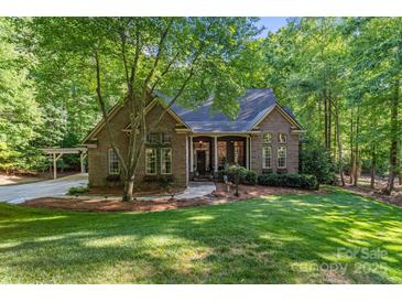 Charming brick home featuring a lush, landscaped front yard and inviting entrance, nestled amongst mature trees at 131 Sierra Woods Dr, Troutman, NC 28166